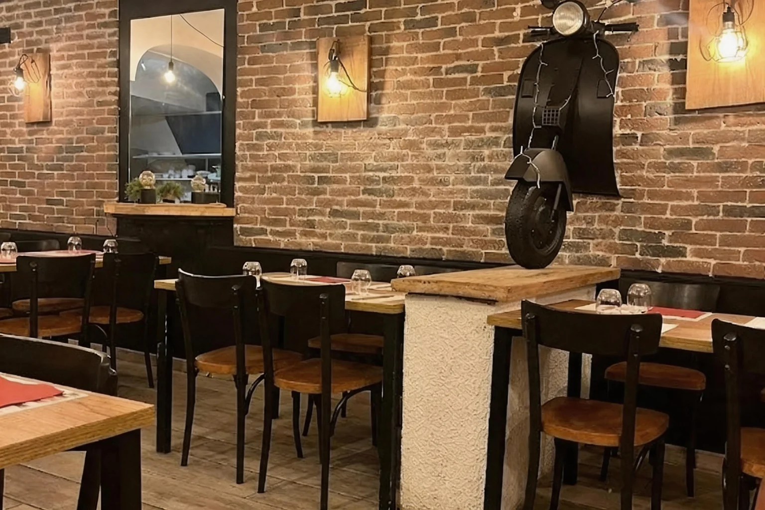 Dining room with brick wall, black scooter on the wall, wooden wall lamps, tables and chairs