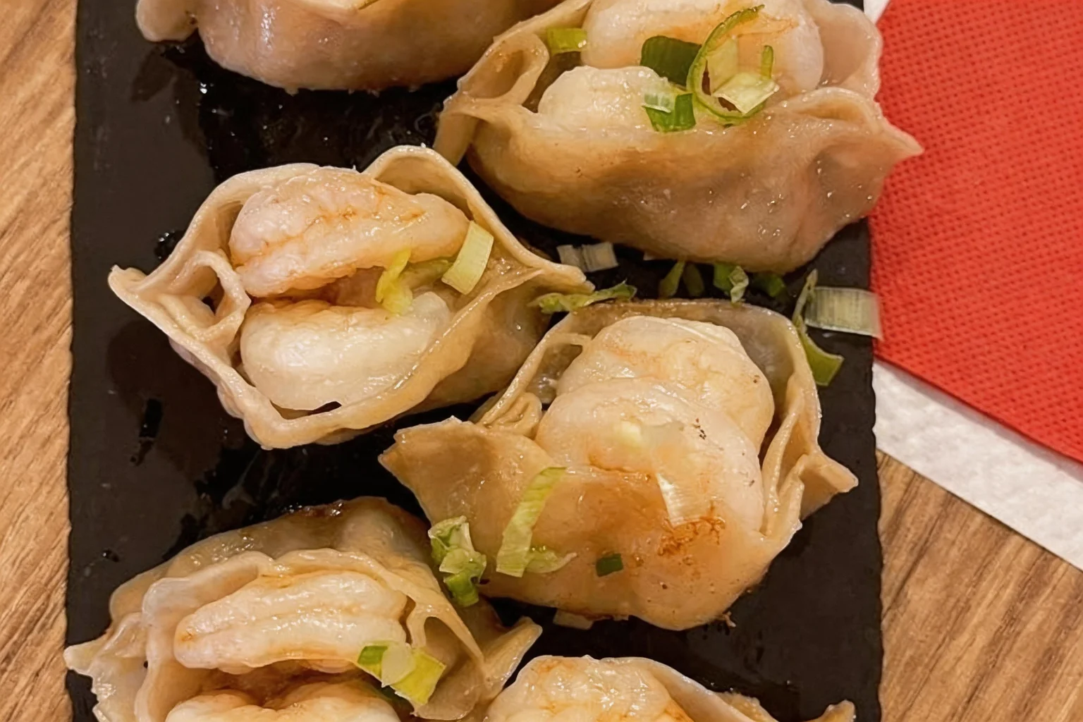 Shrimp dumplings on a black slate, wooden table